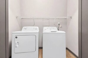 A laundry room with two front-loading washing machines and a drying rack above. - Balcony Retreat Near USC, The Vista & Downtown (Columbia)