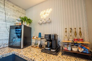 A kitchenette with a coffee machine, a refrigerator, and a herringbone-patterned wall.