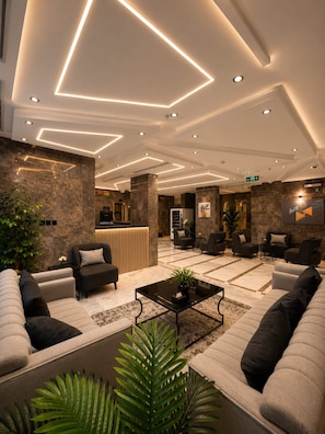 A modern lobby with a reception desk, sofas, and a coffee table. - tamouh almuttahida hotels (madinah)