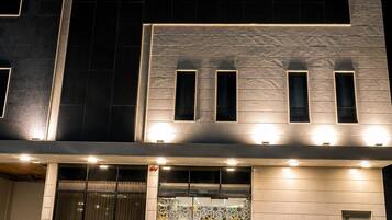 Fachada moderna de edificio con señalización iluminada en inglés y árabe, que presenta un patrón geométrico en la entrada.