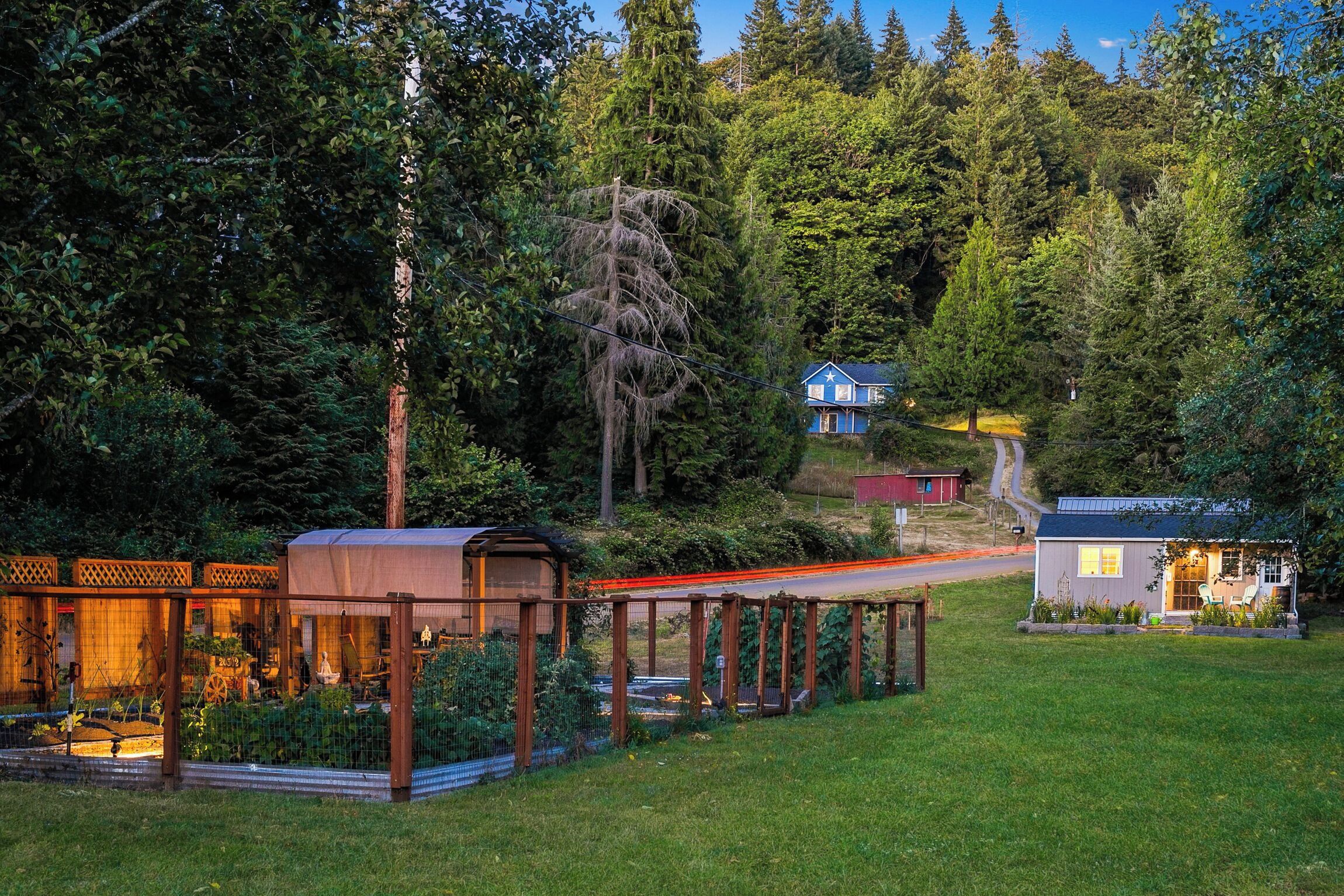 A residential property with a covered outdoor area, a small house, and a pathway leading to a larger building.