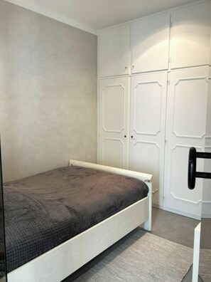 Ein Schlafzimmer mit einem Bett, einem Kleiderschrank und einem Sessel.