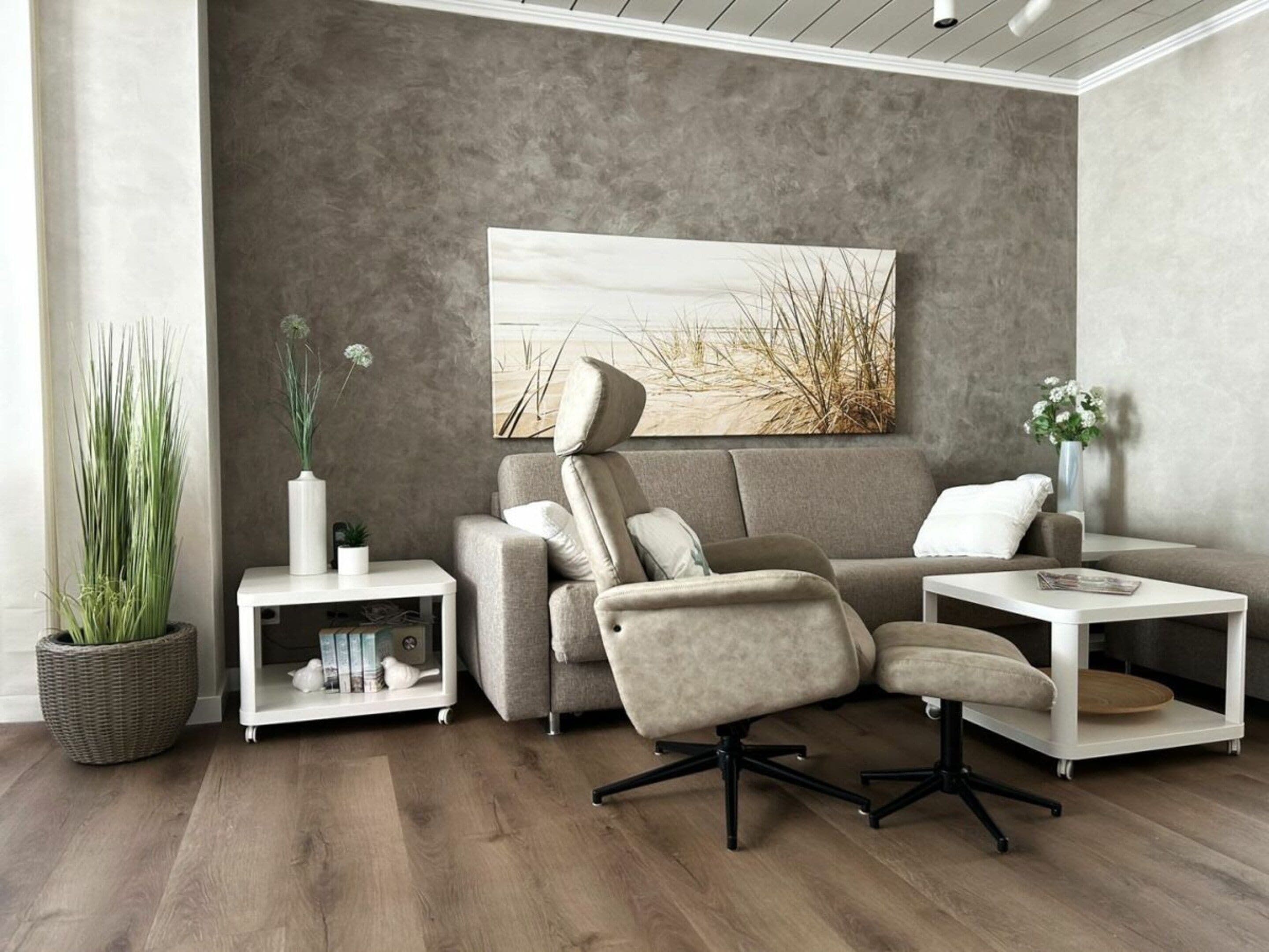 A modern living room with a sectional sofa, a white side table, a floor lamp, and a large abstract painting on the wall.