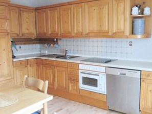 Eine Küche mit Holzausstattung, einem Spülbecken, einem Herd, einem Backofen und einem Geschirrspüler.