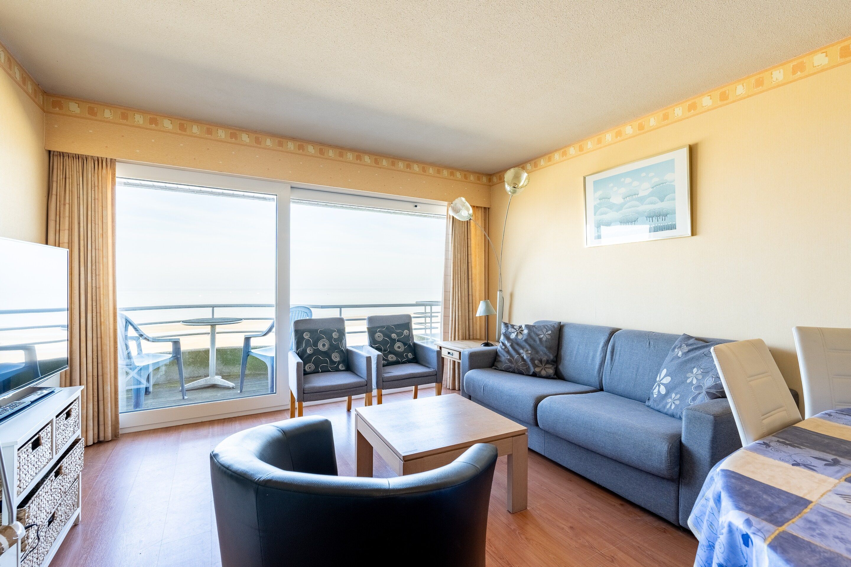 Ein Hotelzimmer mit Balkon, einer Couch, einem Couchtisch und einem Fernseher.