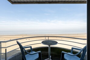 A balcony with a view of a beach, a round table, and two chairs. - Seaside Apartment in Blankenberge With Sea Views (Blankenberge)