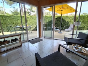 Quarto com porta de vidro deslizante que dá para área externa com mesa, cadeiras e um guarda-sol amarelo.