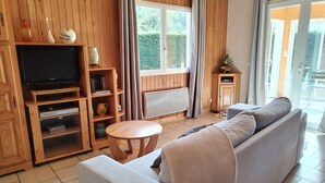 Una habitación con paneles de madera, un sofá, un televisor y una pequeña mesa.