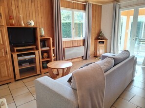 Quarto com painéis de madeira, um sofá, uma televisão e uma pequena mesa.