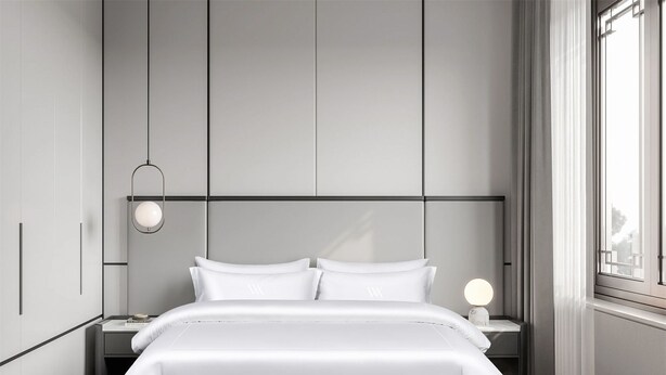 Un dormitorio moderno con una cama grande, una mesita de noche, una lámpara de pared y una ventana con cortinas.