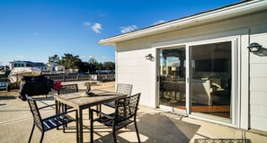 Eine Terrasse mit Tisch und Stühlen, einem überdachten Kinderwagen und Blick auf einen Poolbereich.