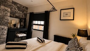 Quarto com uma cama grande, escrivaninha, radiador e janela.