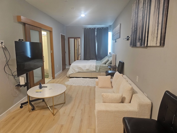 Quarto de hotel com cama, sofá, televisão e escrivaninha.