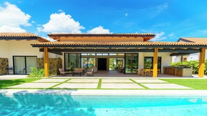 Een modern huis met een zwembad, grote ramen en een terras.