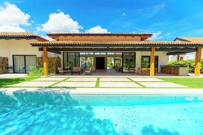 Una casa moderna con piscina, ventanas amplias y un patio.