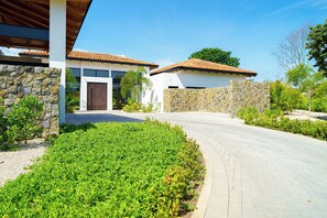 Un edificio moderno con fachada de piedra, techo de tejas y un camino pavimentado que conduce a una entrada con portón.