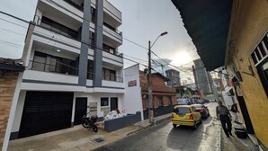 Una estrecha calle urbana con edificios, una motocicleta estacionada y un taxi amarillo.