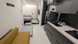 Cocina compacta con estufa integrada, un refrigerador y un pequeño comedor con un banco.