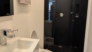 Un baño moderno con lavamanos, inodoro y cabina de ducha de vidrio.