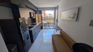Una cocina compacta con electrodomésticos modernos, un comedor con banco y vistas al balcón exterior.