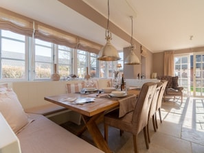 A dining area with a wooden table, chairs, and hanging pendant lights. - Holiday Home in Borgsum With Swimming Pool (Borgsum)