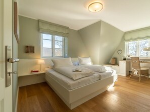 Ein Schlafzimmer mit einem Bett, Nachttischen, einem Schreibtisch und einem Sessel.
