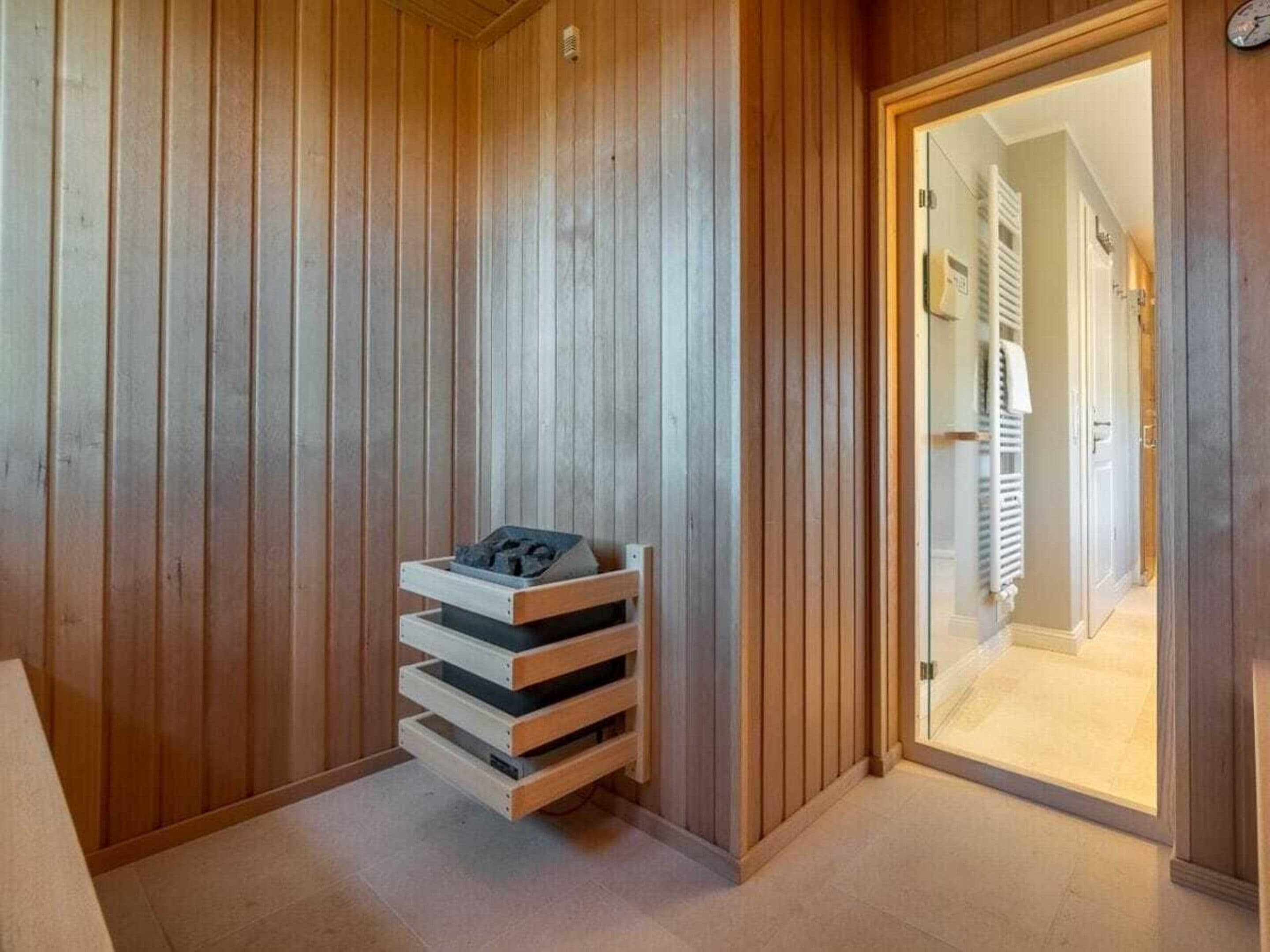 Quarto com paredes revestidas de madeira, um banco embutido com espaço para guardar objetos e uma porta que dá para outro cômodo.