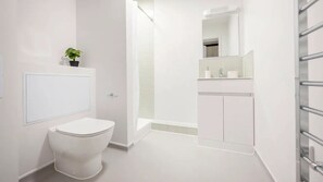 Ein modernes Badezimmer mit Toilette, Dusche und Waschbecken mit Spiegel.