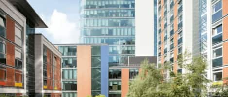 A modern building with a glass facade, a wooden deck, and a bench.