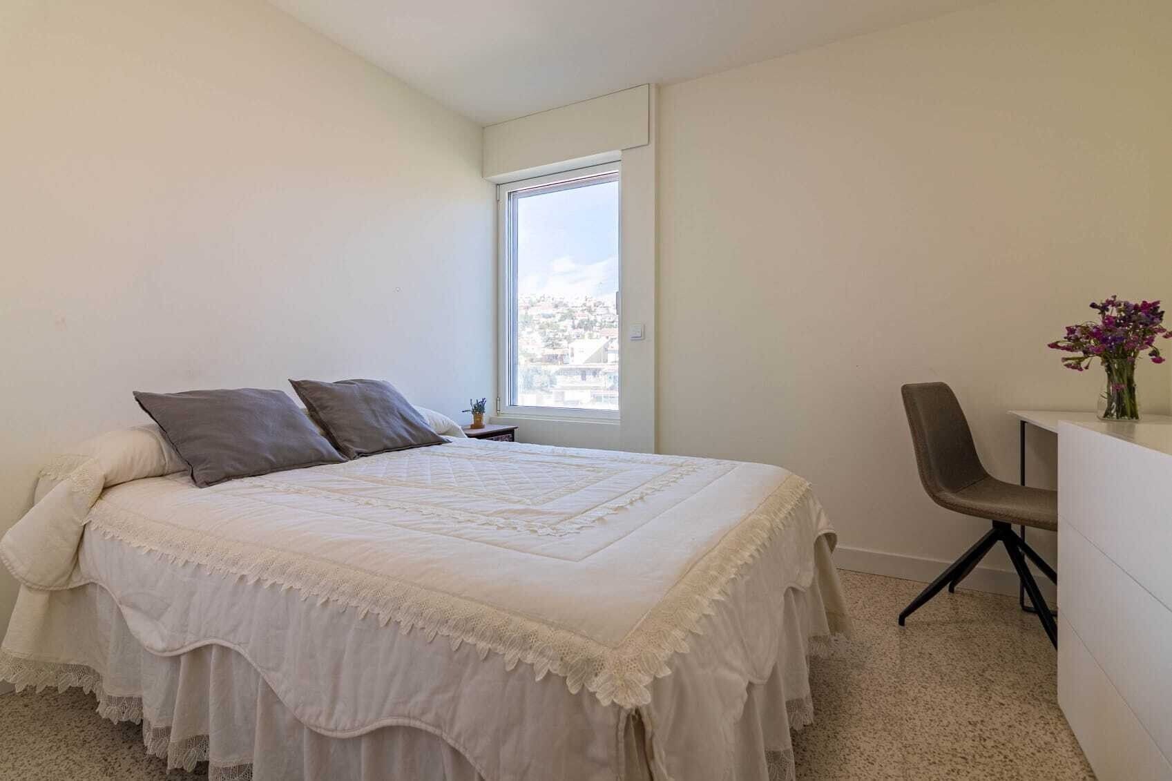 Ein Schlafzimmer mit Bett, Stuhl, Schreibtisch und Fenster.