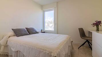 Ein Schlafzimmer mit Bett, Stuhl, Schreibtisch und Fenster.