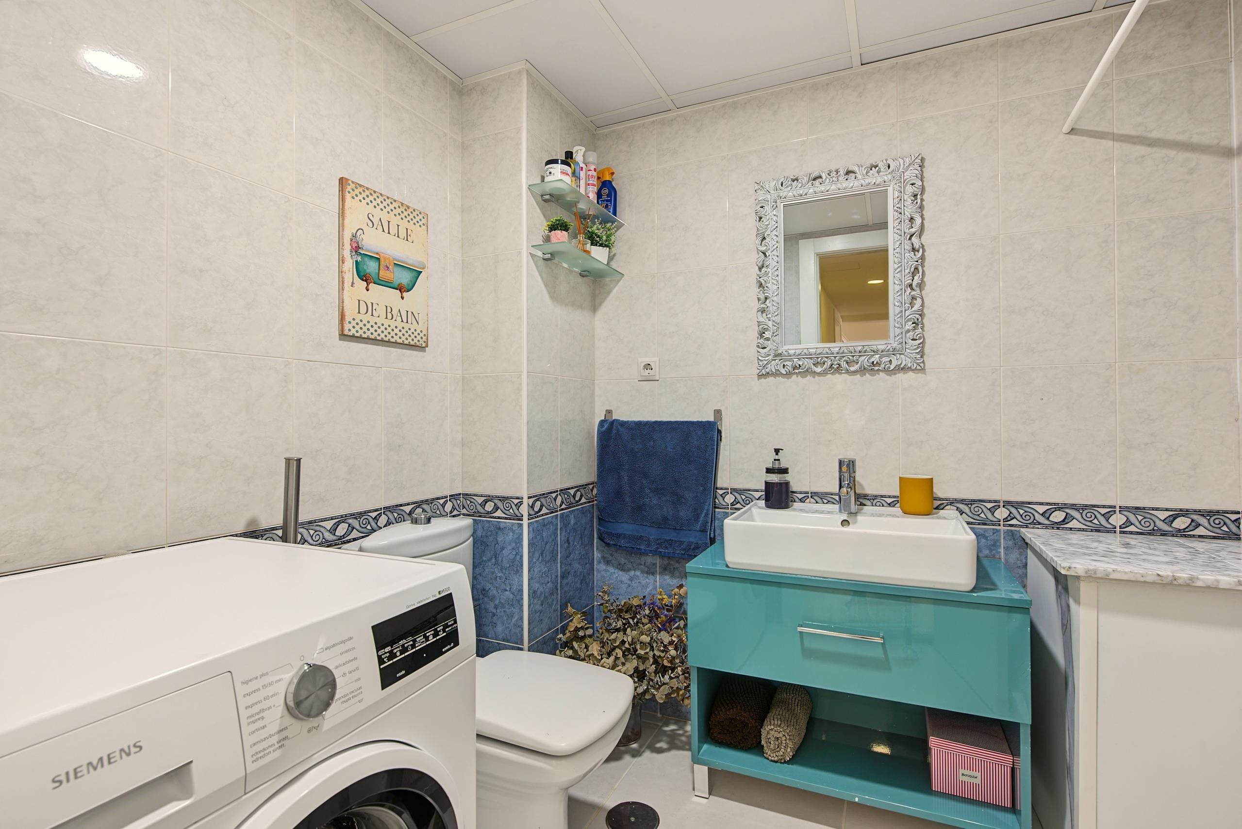 Un baño con lavadora Siemens, un lavabo, un inodoro y un espejo.