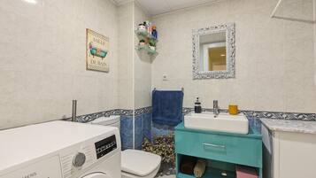 Un baño con lavadora Siemens, un lavabo, un inodoro y un espejo.