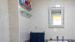 Ein Badezimmer mit einem weißen Waschbecken, einem Spiegel mit aufwändigem Rahmen und einem blauen Handtuch an einem Wäscheständer.