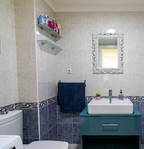 A bathroom with a white sink, a mirror with an ornate frame, and a blue towel hanging on a rack. - Apartment 'Piso Soleado Cerca De La Playa' with Balcony, Wi-Fi and Air Conditioning (Málaga)