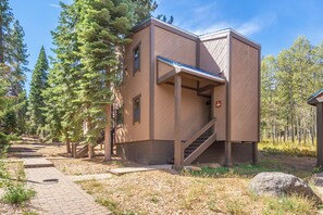 A modern building with a unique architectural design, featuring a sloped roof and a staircase leading to the entrance. - Cozy Cabin Condo | Near Northstar Village (Truckee)
