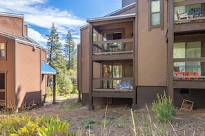 A multi-story building with balconies, a covered outdoor seating area, and a view of trees. - Cozy Cabin Condo | Near Northstar Village (Truckee)