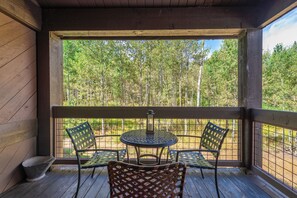 A wooden deck with a table and four chairs, overlooking a forest. - Cozy Cabin Condo | Near Northstar Village (Truckee)