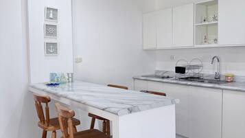 Eine moderne Küche mit Marmorarbeitsplatte, Holzstühlen und einer eingebauten Spüle.