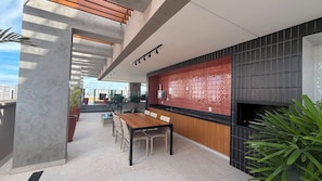 Une cuisine moderne avec un mur de crédence rouge, un coin repas avec une table et des chaises en bois, et une vue sur le paysage urbain.