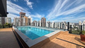 Une piscine sur le toit offrant une vue sur la ville, entourée d’immeubles de grande hauteur.