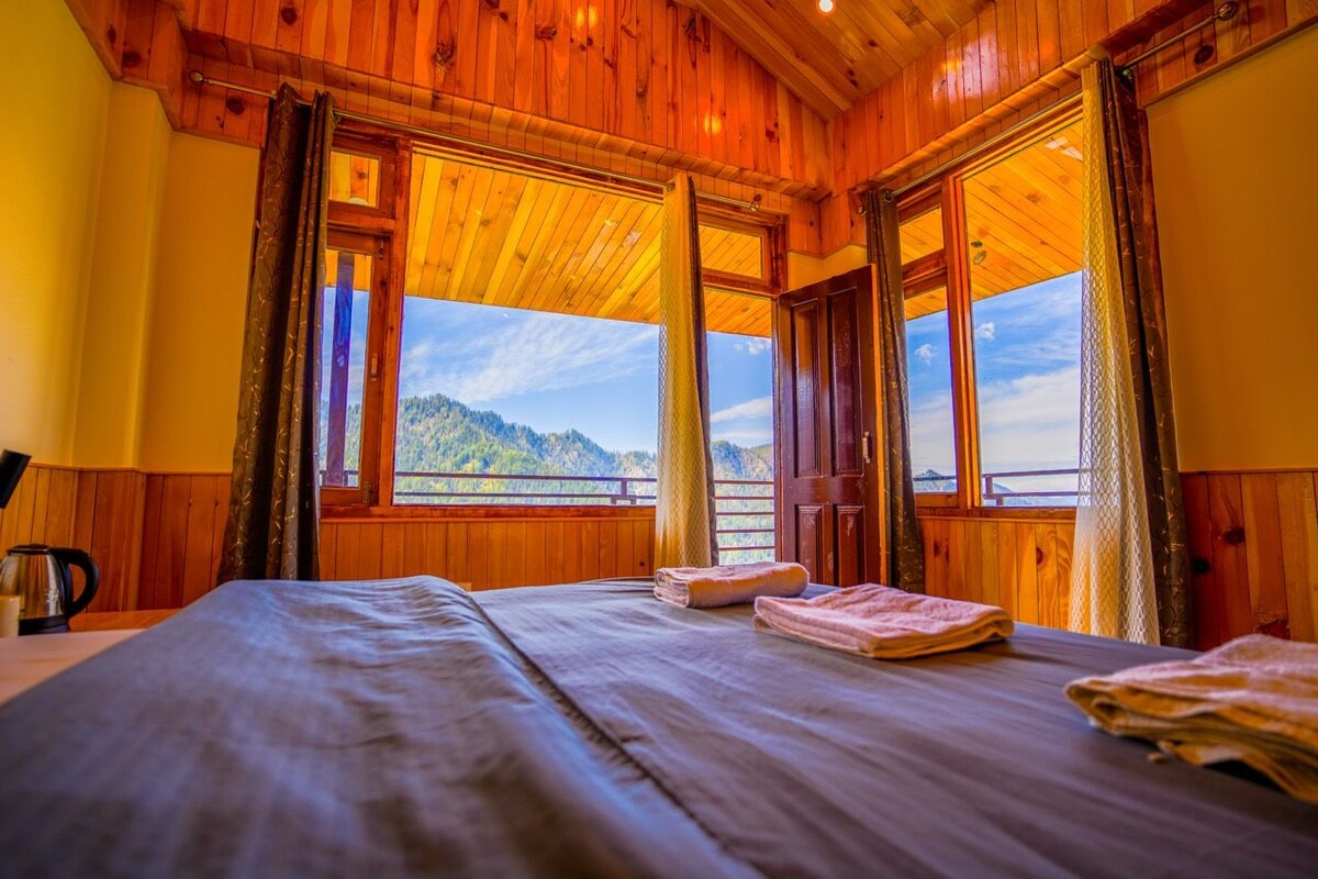 Une chambre avec un lit, une fenêtre donnant sur une montagne et des murs en bois.