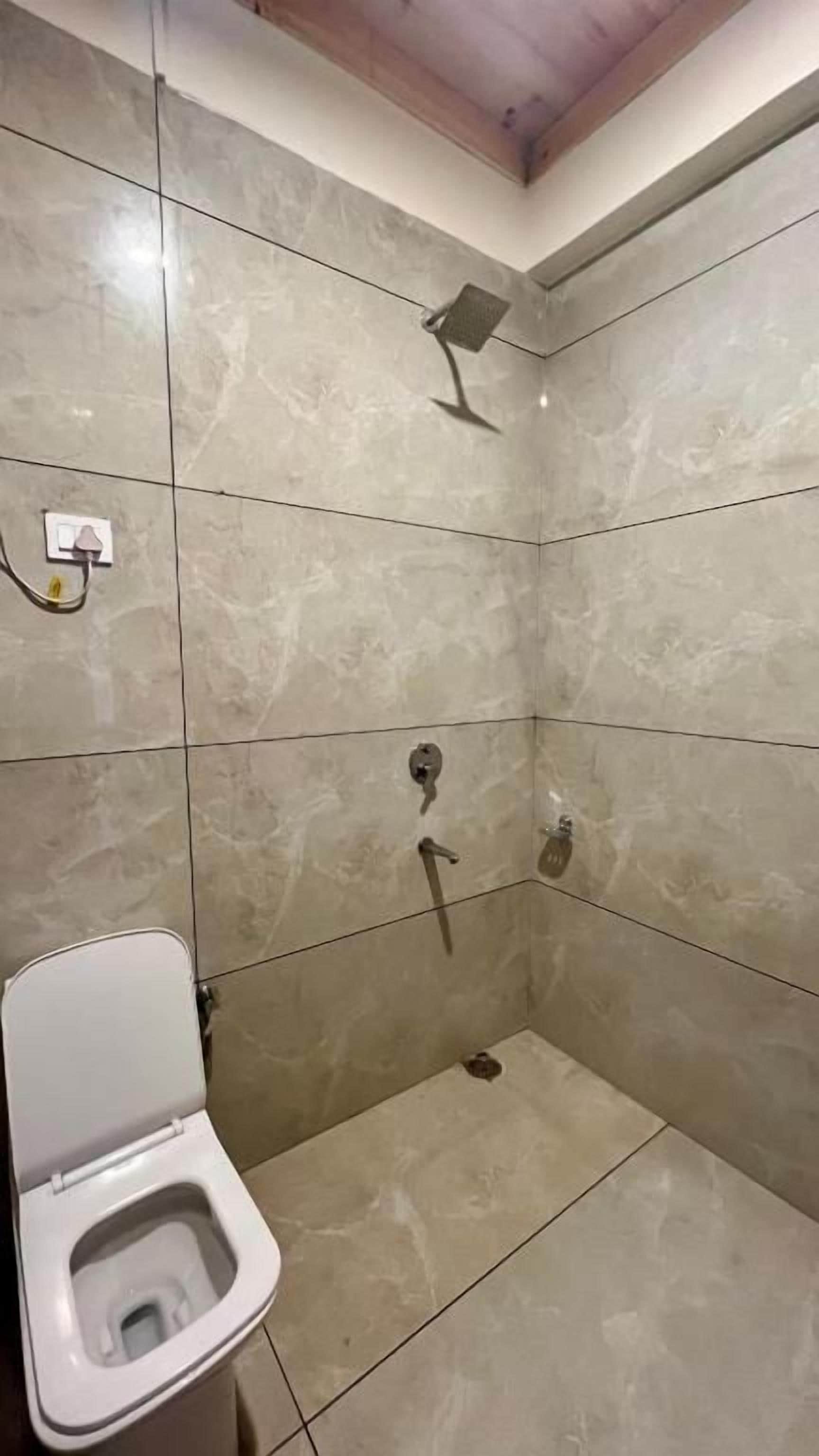 A bathroom with a toilet, a shower, and a tiled floor.