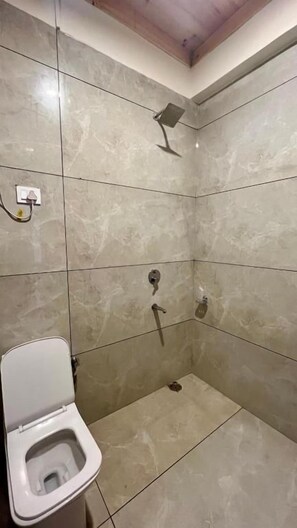Un baño con inodoro, ducha y suelo de baldosas.