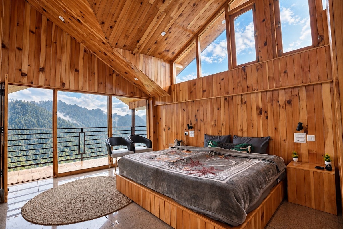 Une chambre avec un grand lit, des murs en bois et un balcon offrant une vue sur la montagne.