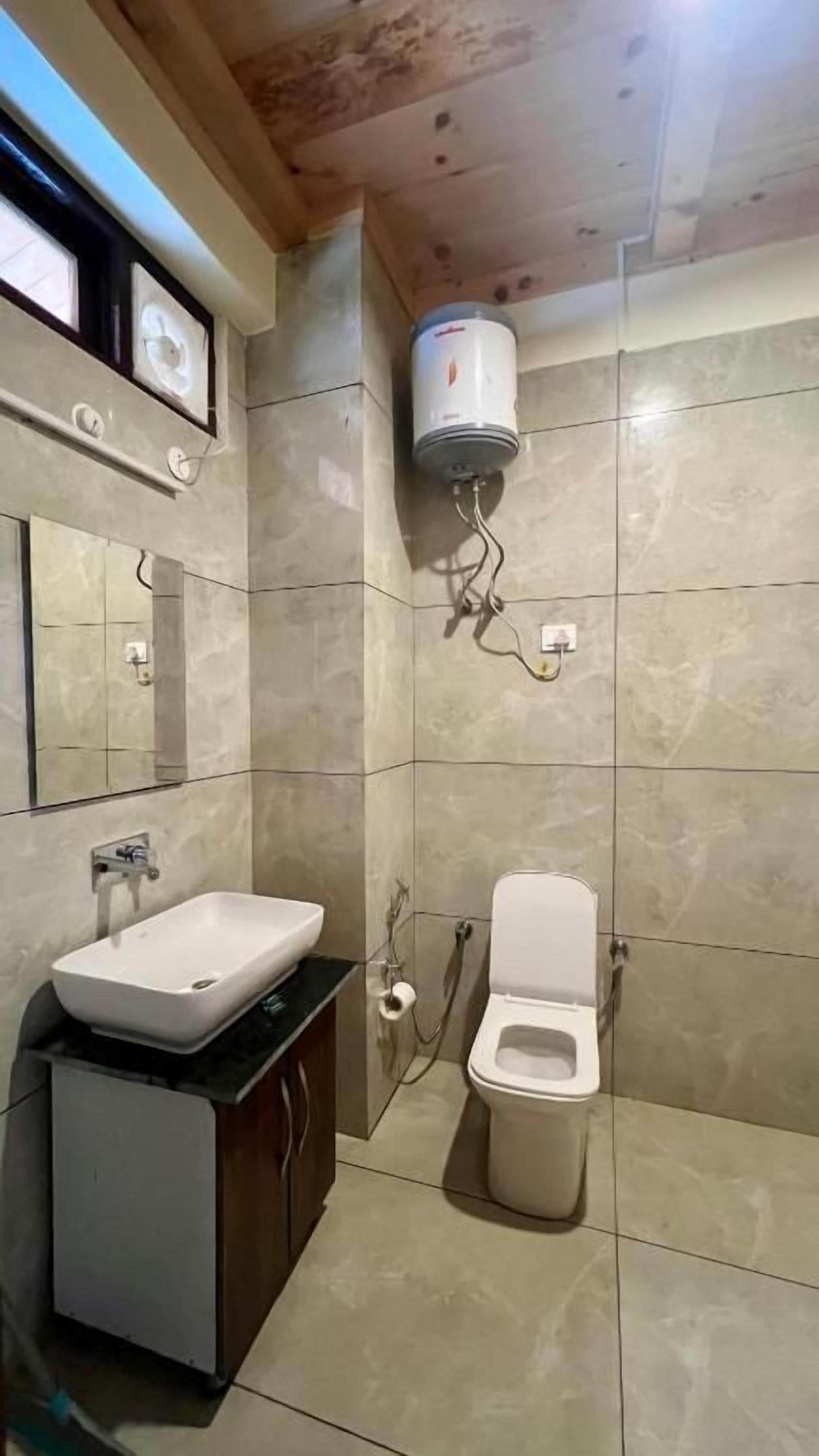 Un baño con lavamanos, inodoro y calentador de pared.