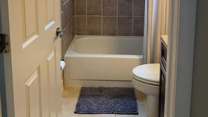 Et badeværelse med badekar, toilet og et vindue.