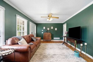 A living room with a brown leather sofa, a wooden cabinet, a television, and a patterned rug.