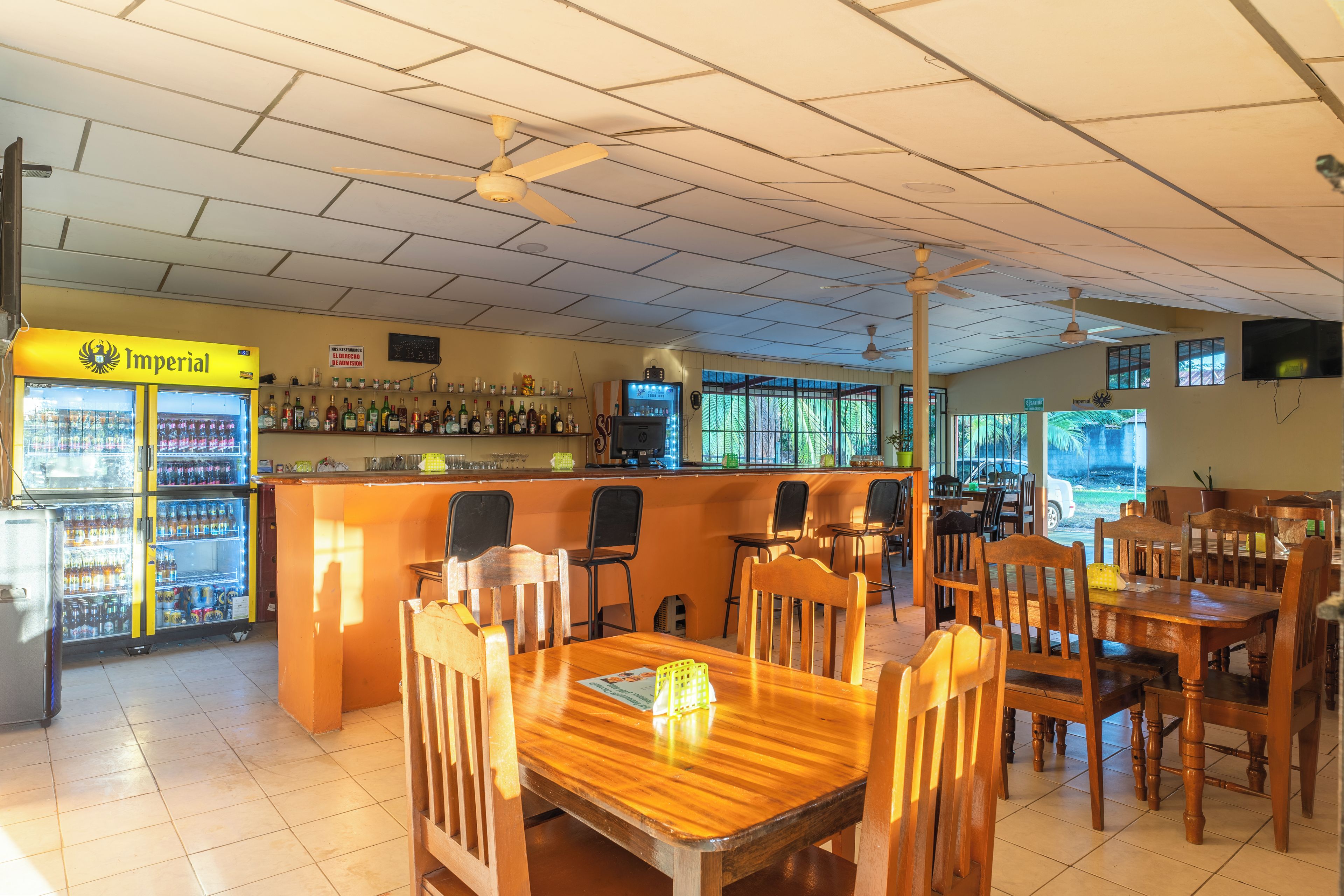 A bar area with a counter, seating, and a refrigerator stocked with beverages.