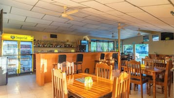 A bar area with a counter, seating, and a refrigerator stocked with beverages.